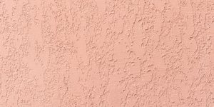 Coral stucco wall texture, peach color background. Abstract grunge artistic backdrop