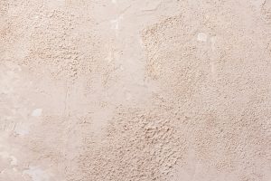 Grunge background with old stucco wall texture of beige color. Empty beige rusty stone surface